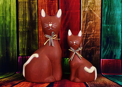 two brown ceramic cat figurines on multicolored wooden surface thumbnail