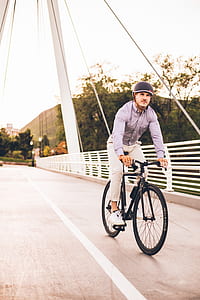 man riding bicycle and wearing helmet on suspension bridge at daytime thumbnail