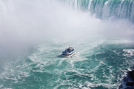 white and blue boat beside waterfall thumbnail
