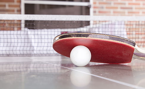 White Pingpong Ball Beneath Red Table Tennis Paddle thumbnail