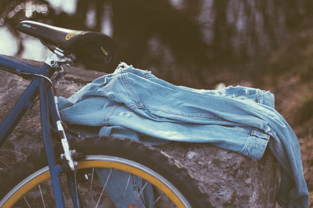 blue denim apparel on rock beside bike during day thumbnail