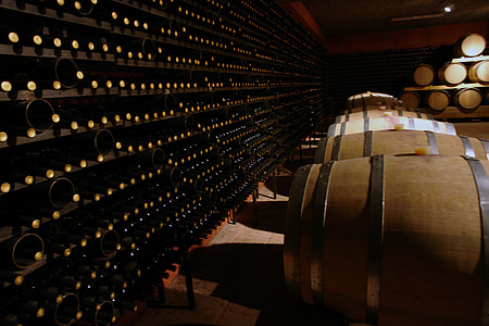 wine bottle on shelf in front of wooden barrels thumbnail