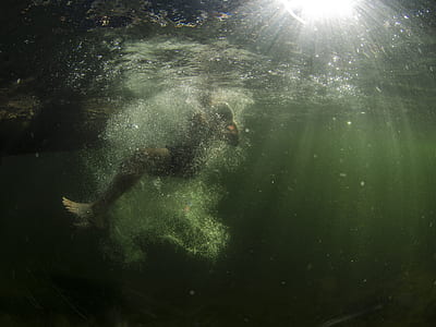 photography of man swimming on body of water thumbnail