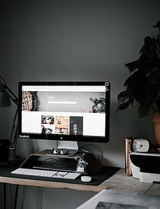 silver iMac on top of brown wooden desk thumbnail