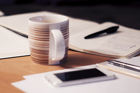 brown and white ceramic cup and iPhone on table thumbnail