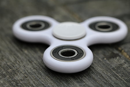 selective focus photography of white fidget spinner on brown surface thumbnail