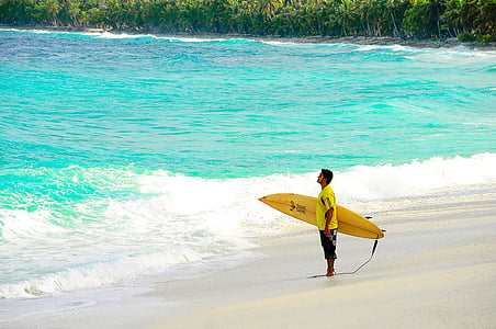man holding yellow surfboard on beach thumbnail