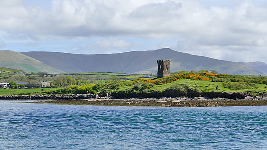 tower on grass field near body of water thumbnail