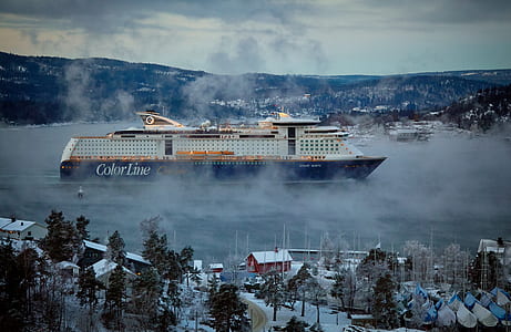 white and blue Color Line cruise ship voyaging between islands with houses thumbnail