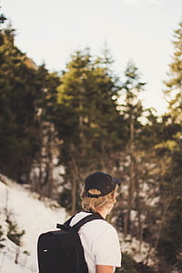 focus photo of man standing carrying black backpack near trees thumbnail