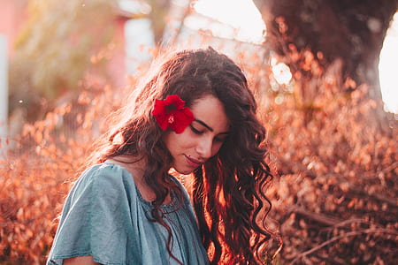 depth of filed photography of woman wearing blue scoop-neck shirt and red hibiscus on ear thumbnail