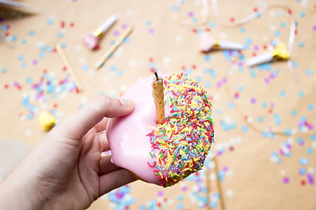 person holding doughnut with sprinkles and candle thumbnail