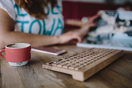 Closeup of female hands typing text on a wireless wooden keyboard thumbnail