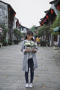 woman in gray coat holding flower arrangement thumbnail