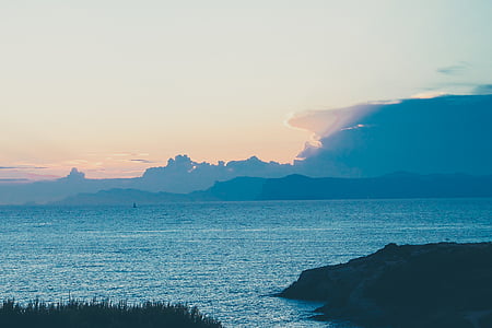 photo of ocean near mountain at daytime thumbnail