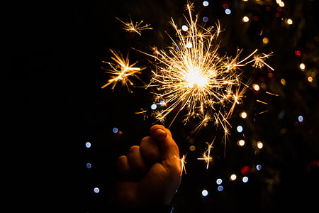 person holding sparkler with background of boke lights thumbnail