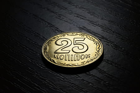 round gold-colored 25 coin on black surface thumbnail