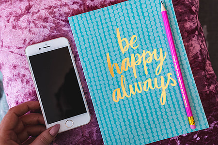 Blue notebook with a pink iPhone, headphones and a sweet bun thumbnail
