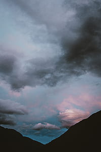 silhouette photography of hill under gray clouds thumbnail