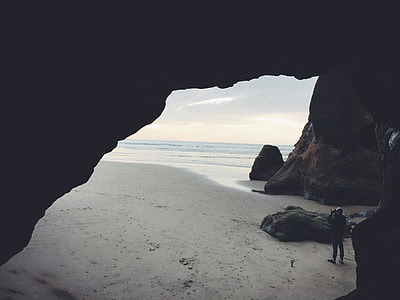 man standing in cave facing sea at daytime thumbnail