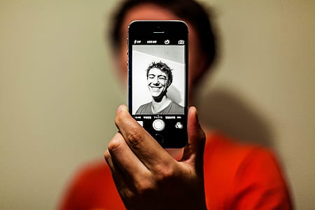 Man in Red Shirt Having Selfie on His Iphone in Grayscale Mode thumbnail