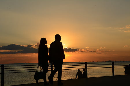 man and woman walking near sea during golden hour thumbnail