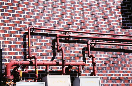 red pipeline beside red brick wall thumbnail