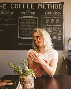 woman holding book while sitting near chair thumbnail