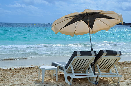 two white sun loungers under umbrella on seashore thumbnail