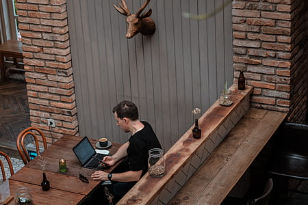 Man Sitting in Front of His Laptop White Looking at His Phone thumbnail