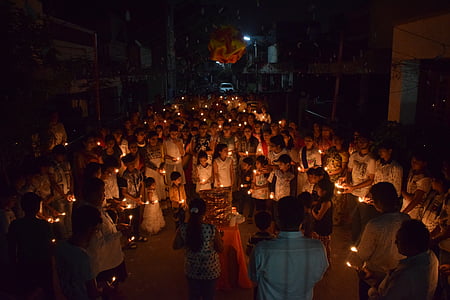 group of people holding candles while huddling thumbnail