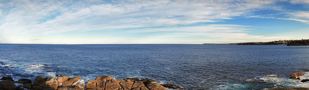 rocky hill viewing calm sea under blue skied at day time thumbnail