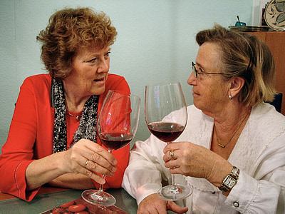 two women holding wine glasses while looking to each other thumbnail