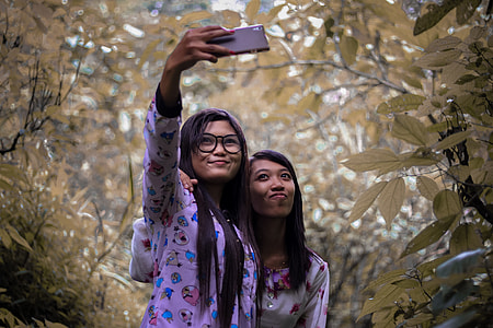 two women taking picture outdoors thumbnail