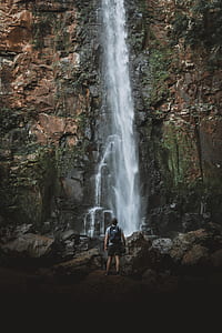 time lapse photography of man facing waterfalls thumbnail