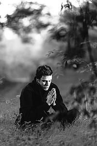 grayscale photograph of man sitting on grass thumbnail