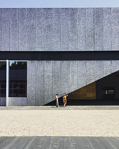three women standing beside gray concrete building thumbnail