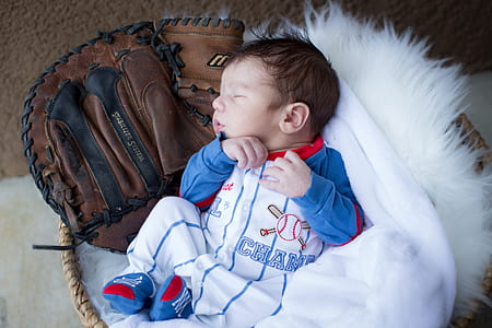 baby sleeping on basket beside catchers mitt thumbnail