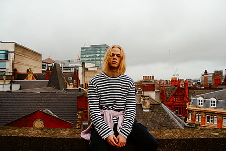 man wearing striped shirt sitting on roof thumbnail