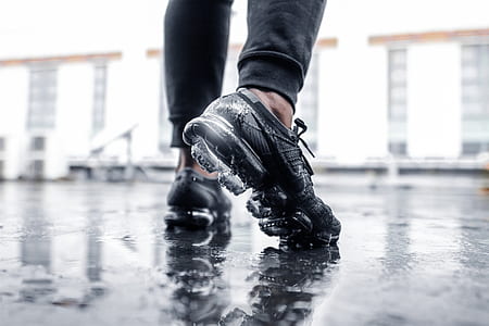 person wearing black Nike Air Max shoes while stepping in water thumbnail