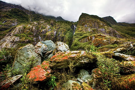 low-angle photography of green and brown mountain under white clouds during daytime thumbnail