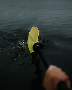 person holding black and yellow paddle at daytime thumbnail