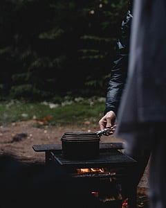 person in black jacket cooking on charcoal grill thumbnail