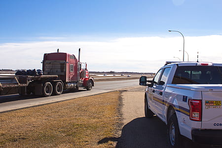 red semi trailer truck on road near white pickup truck thumbnail