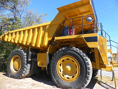 yellow earth mover parked near tree thumbnail
