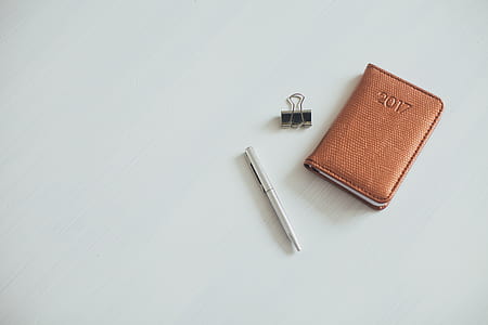 gray twist pen beside brown leather wallet and paper clip on white surface thumbnail