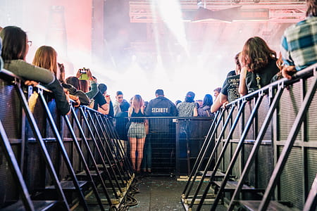 A view of concert audience from crowd control barrier with smoky stage in the background thumbnail