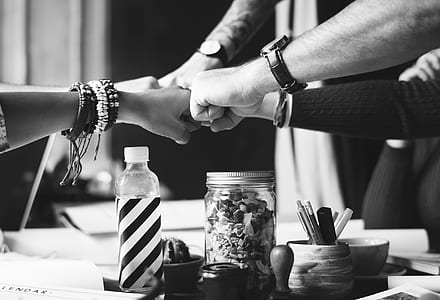 grayscale photo of four persons sticking their fists thumbnail