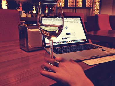 glass of champagne beside MacBook Pro on brown wooden desk thumbnail