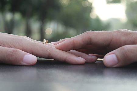 person touching other person's hand wearing gold-colored ring thumbnail